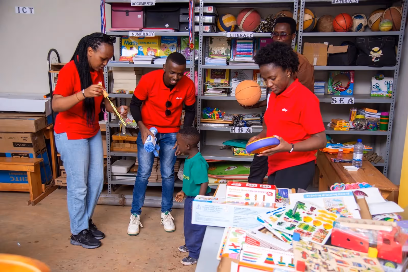 Tubiteho teacher demonstrating multi-sensory learning methods with support from Deriv volunteers in a classroom setting.‍