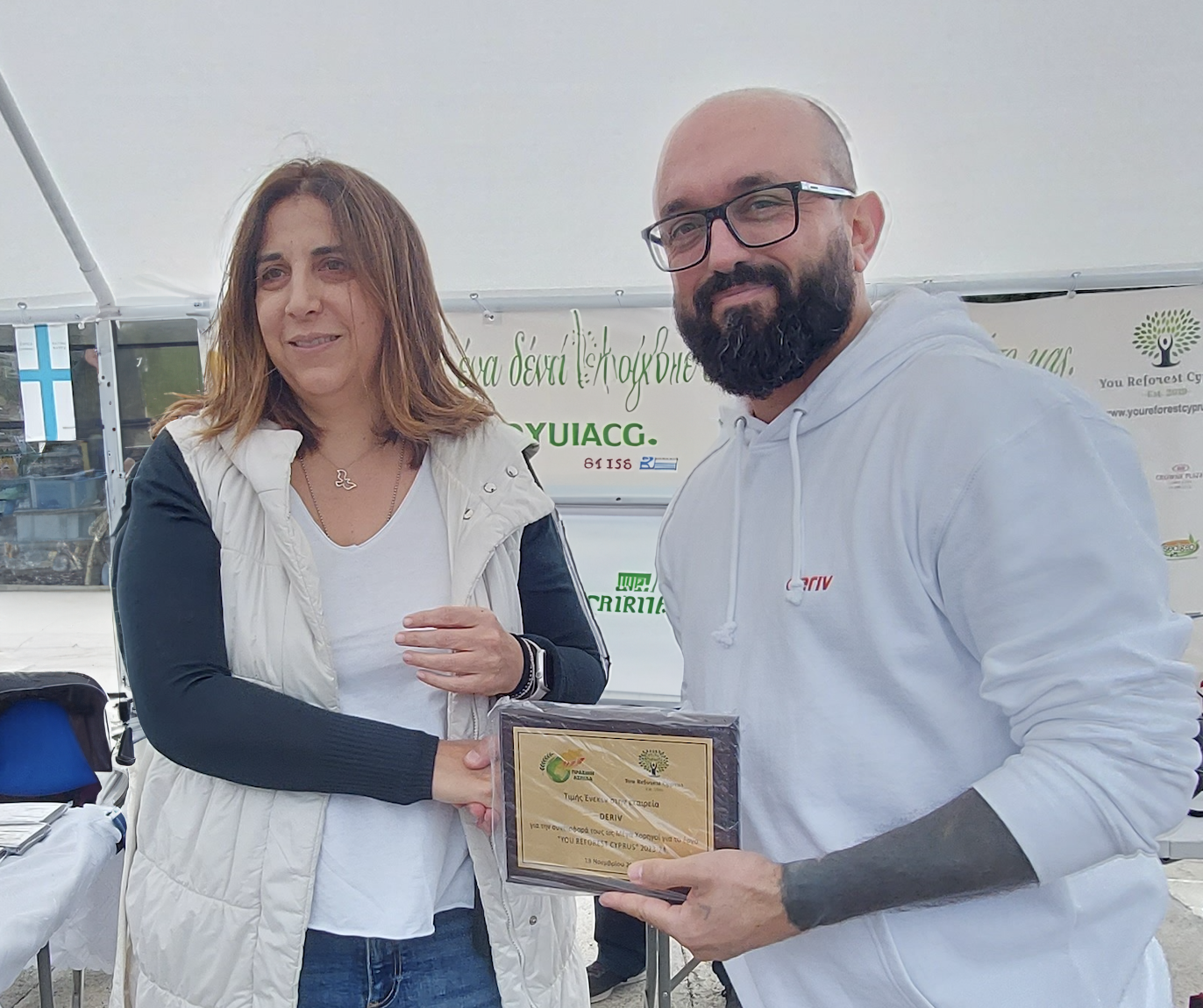 Geo Nicolaidis holding the plaque with a leaf emblem.