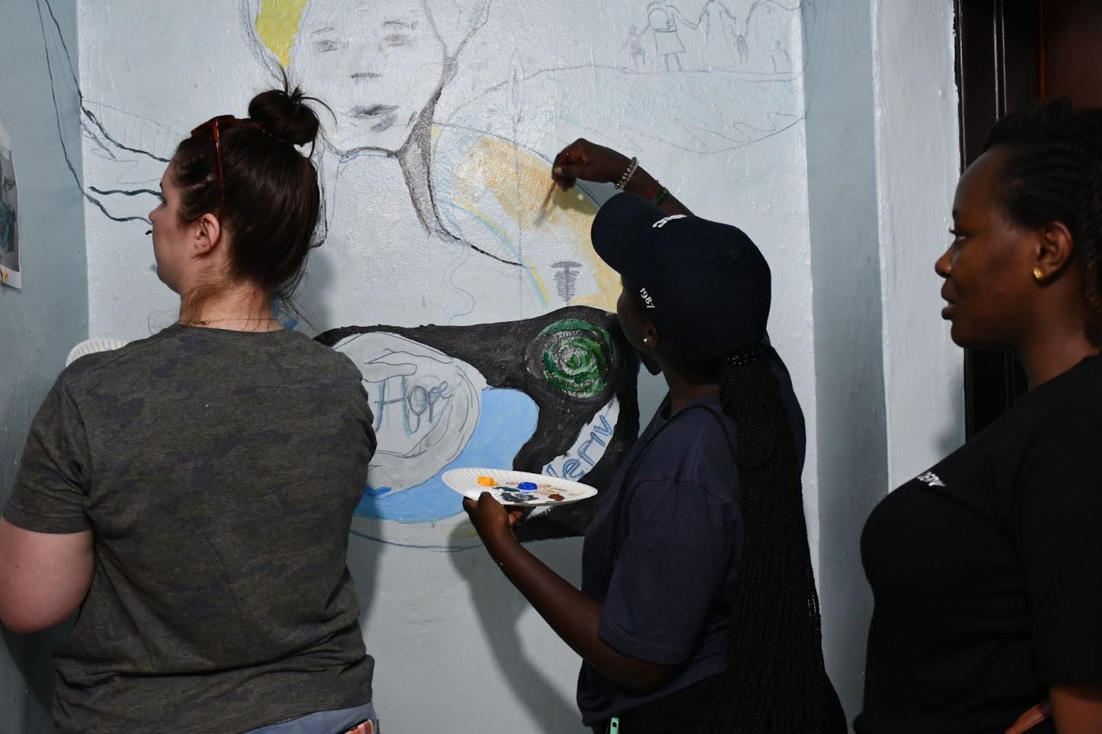 Deriv Ruanda-Mitarbeiter und ein Mitarbeiter von DuHope beim Streichen der Werkstatt für das Ruanda Afrika CSR-Programm