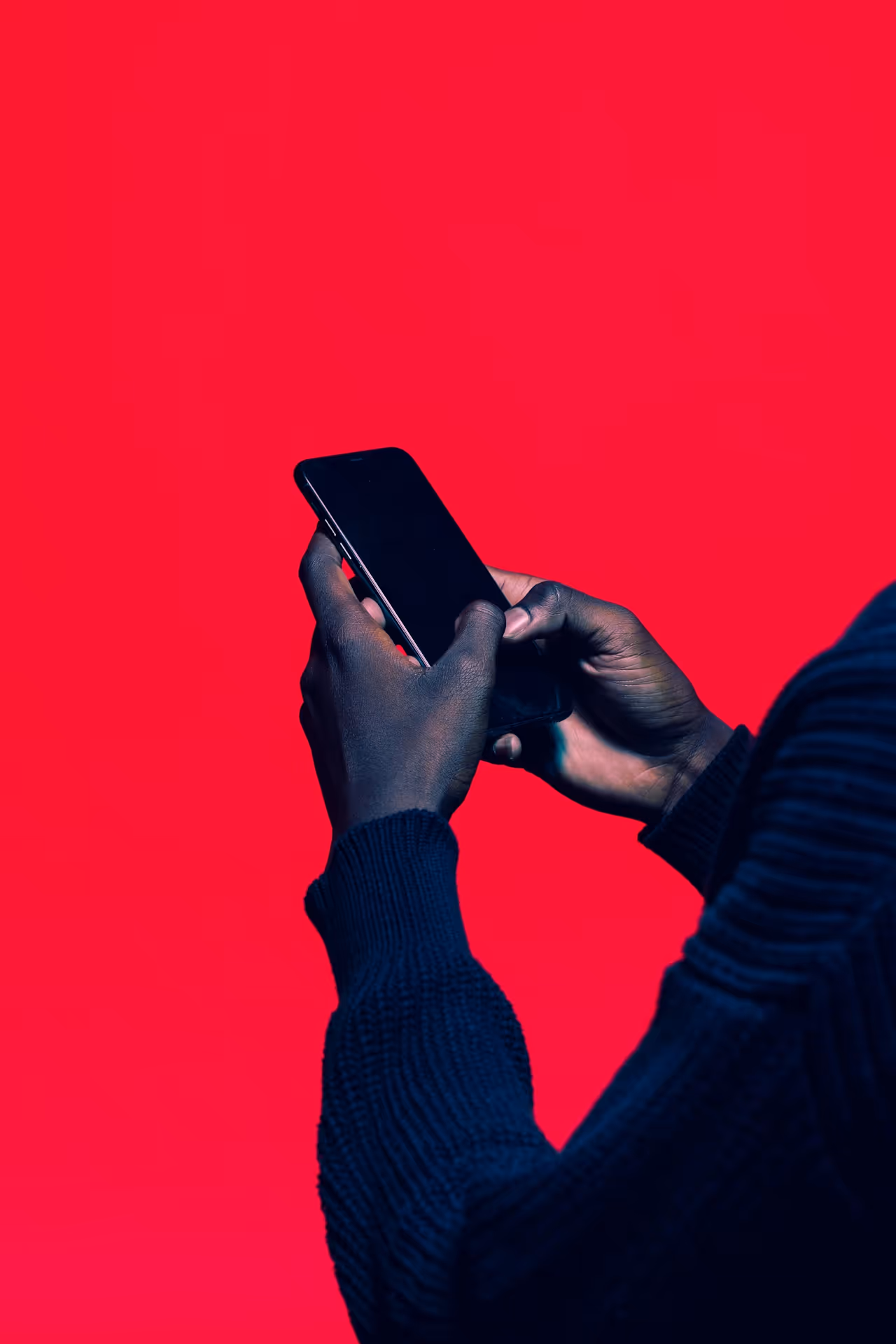 Zwei Hände tippen auf einem Smartphone vor rotem Hintergrund