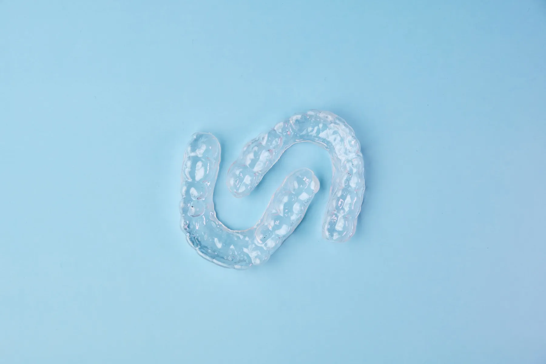 Clear dental aligners on a light blue background.