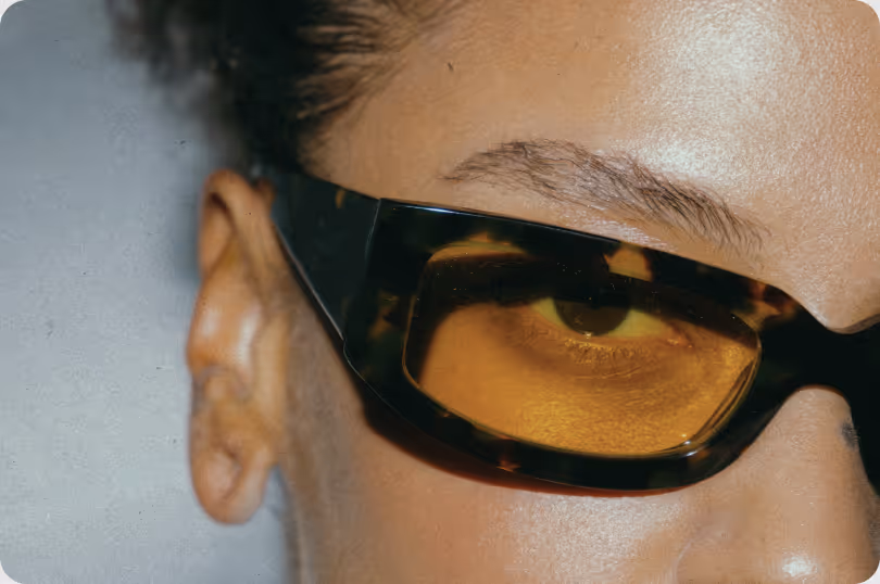 Close-up of a person's face wearing large tortoiseshell sunglasses with amber lenses.