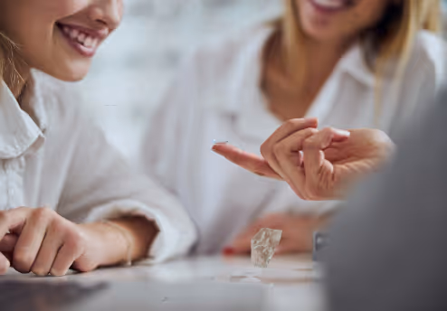 Close-up of a person holding a contact lens on their fingertip with another person smiling nearby.