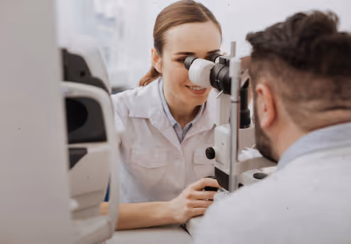 Female optometrist using a slit lamp to examine a male patient's eyes during an eye exam.