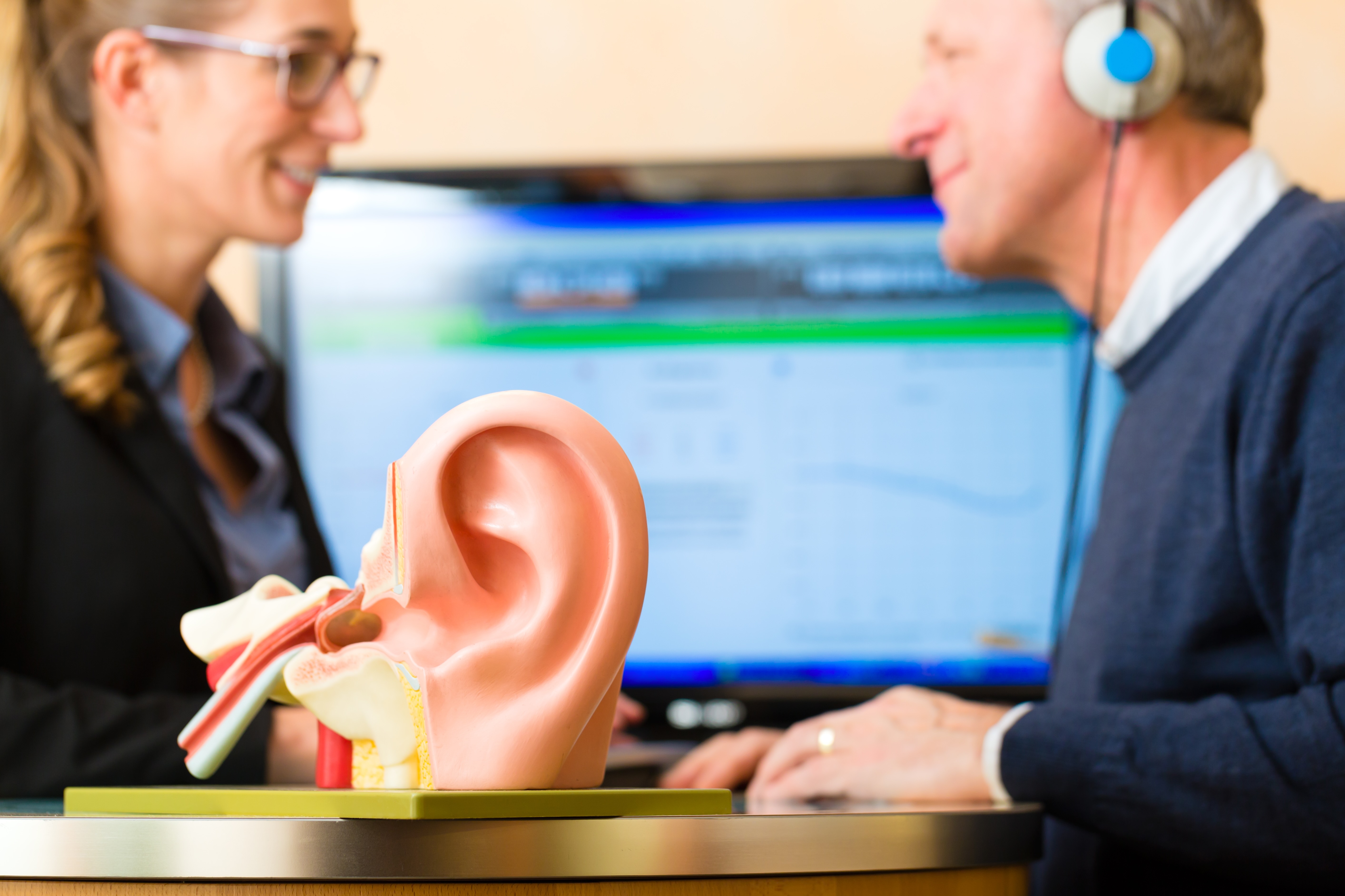 man having hearing test and scientific ear model