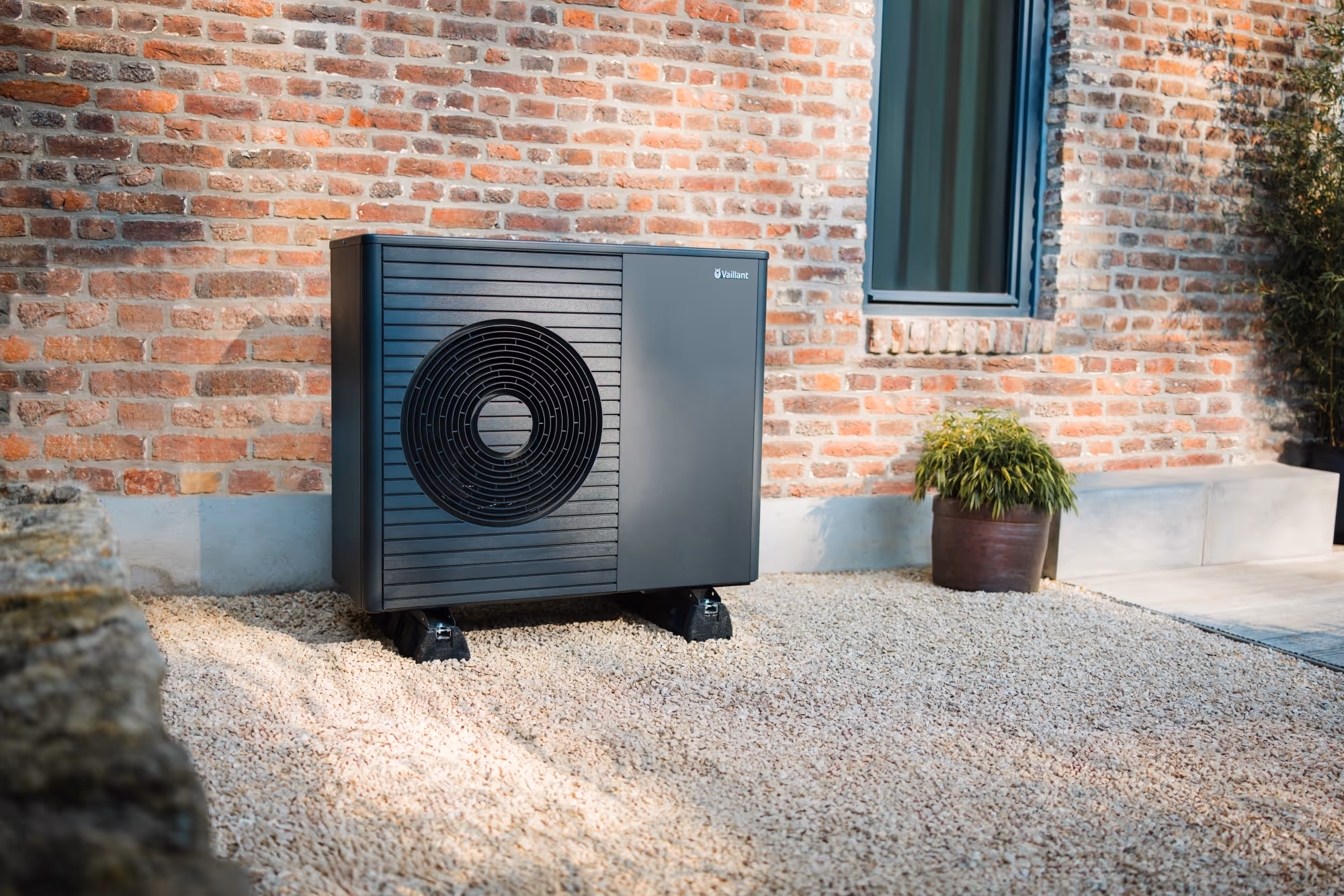 Schwarze Vaillant arotherm Plus Wärmepumpe vor Backsteinhaus.