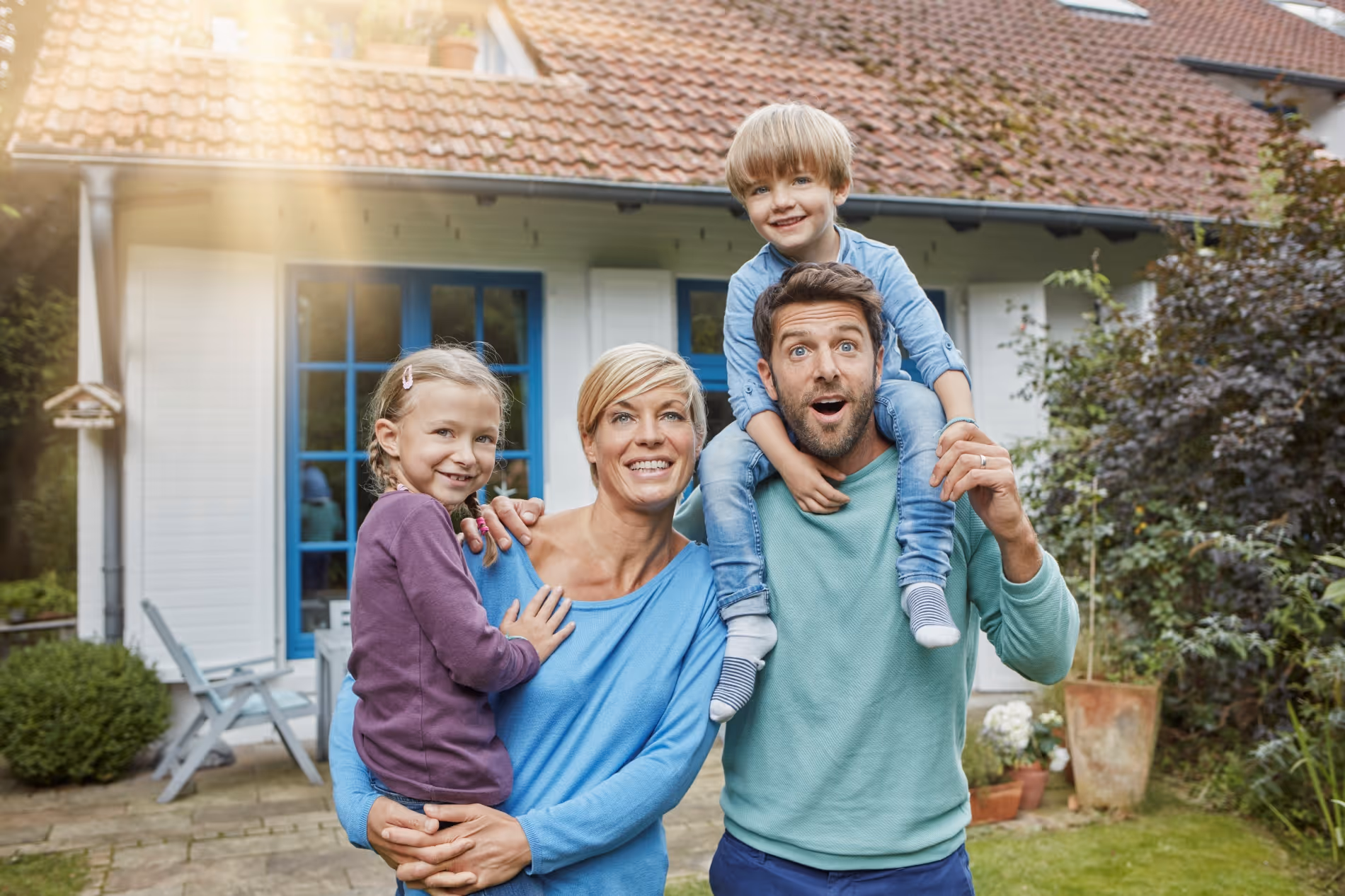 Vierköpfige Familie vor Eigenheim