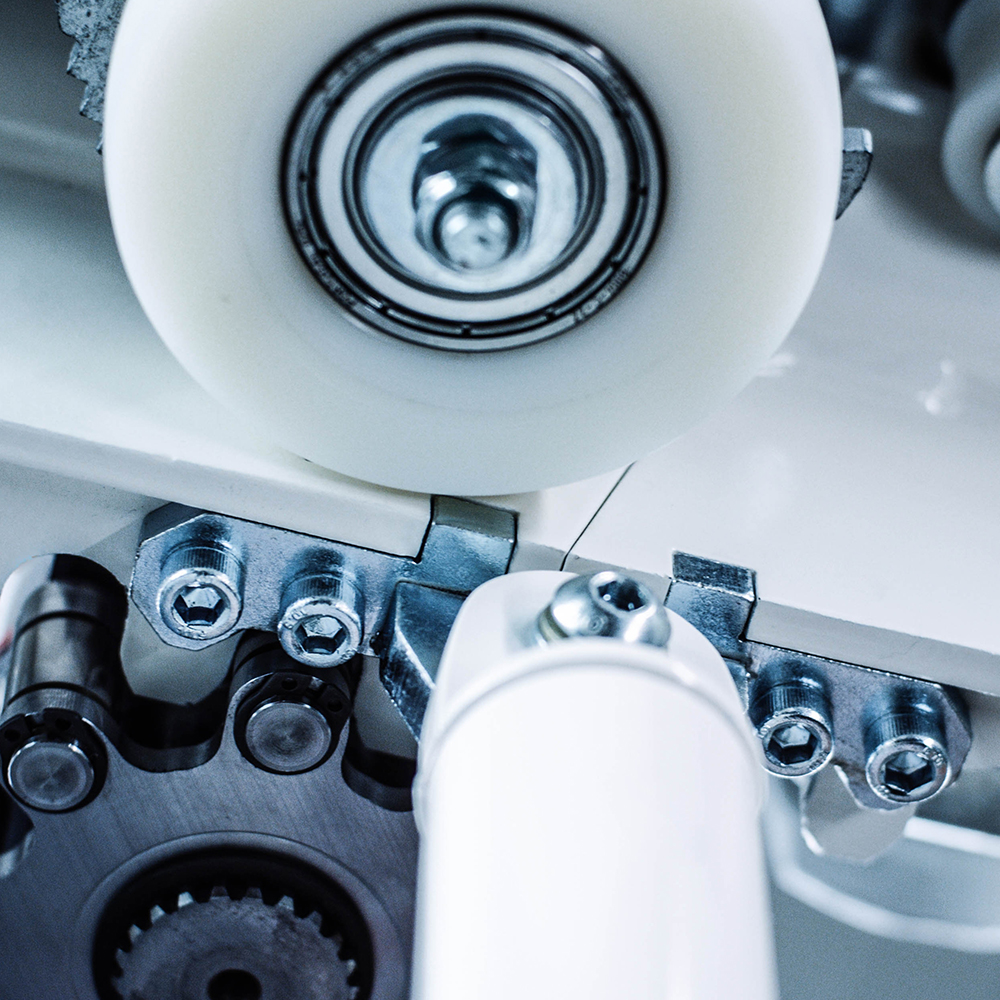 A close-up image of a white wheel with a black center and silver hub, surrounded by a white metal gear and a silver bolt, showcases intricate details and a focus on mechanical components.