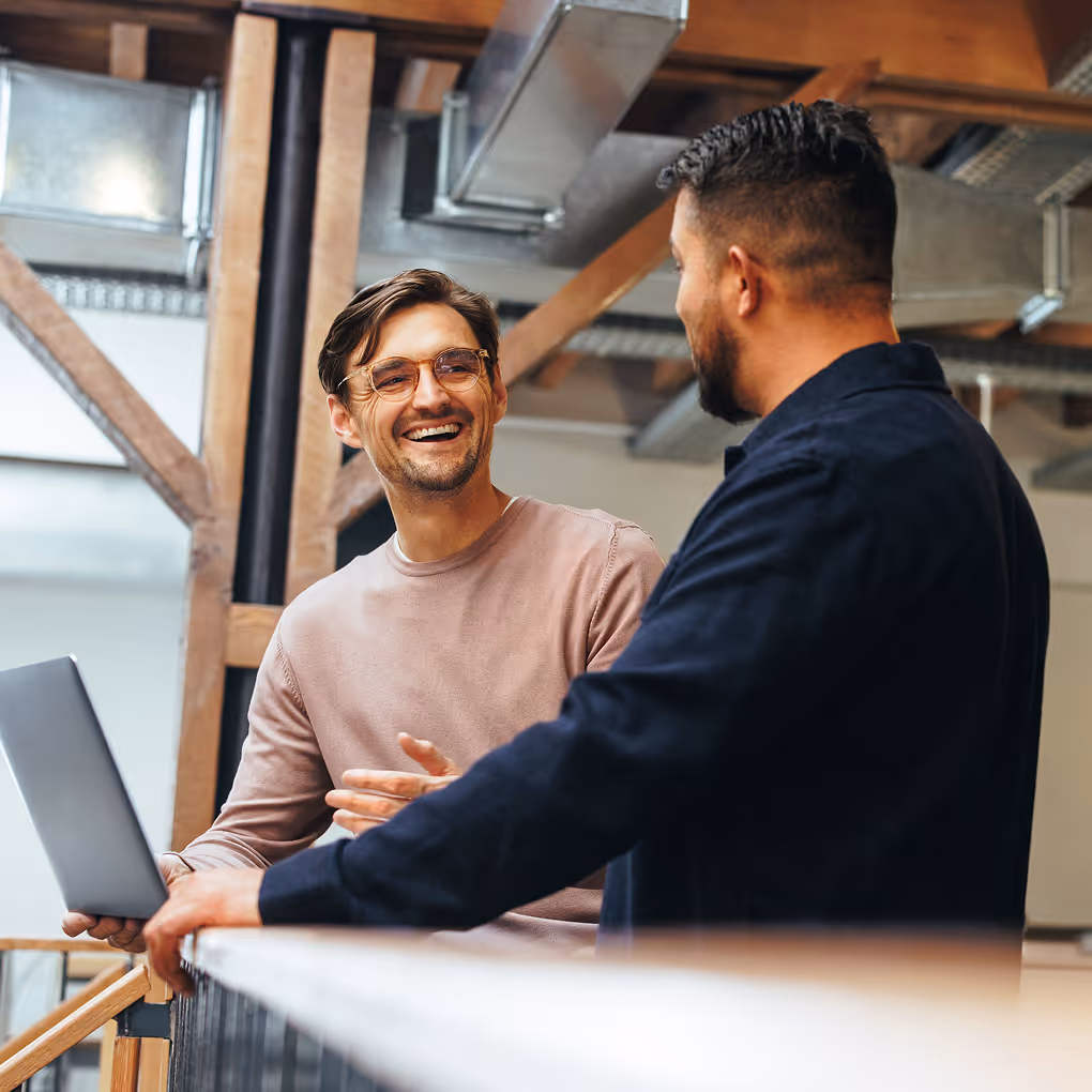 Zwei Männer unterhalten sich lachend über ein Xurrent Projekt im Büro von Expertize