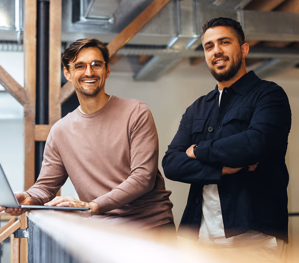 Zwei lächelnde Männer von Expertize mit einem Laptop