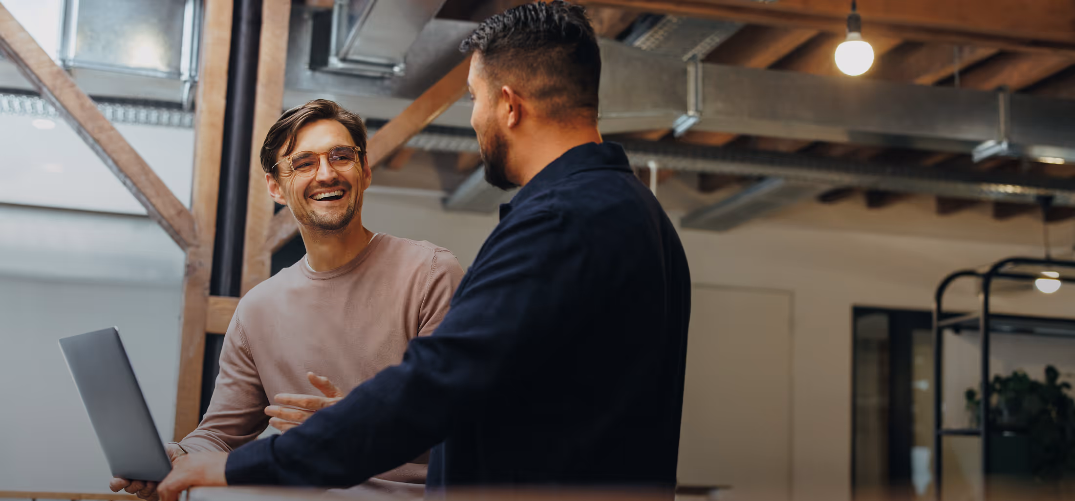 Zwei Männer unterhalten sich lachend über ein Xurrent Projekt im Büro von Expertize
