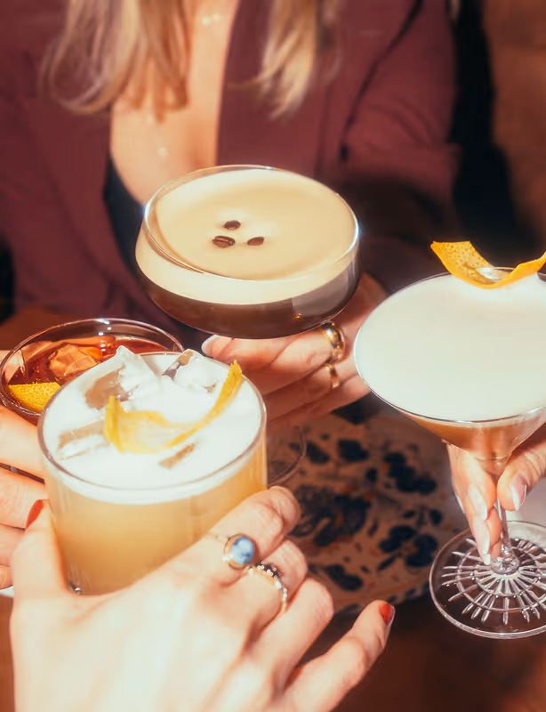 Freund*innen stoßen mit Cocktails im Italian Shot Glockenbach an – Espresso Martini, Sour und Martini.