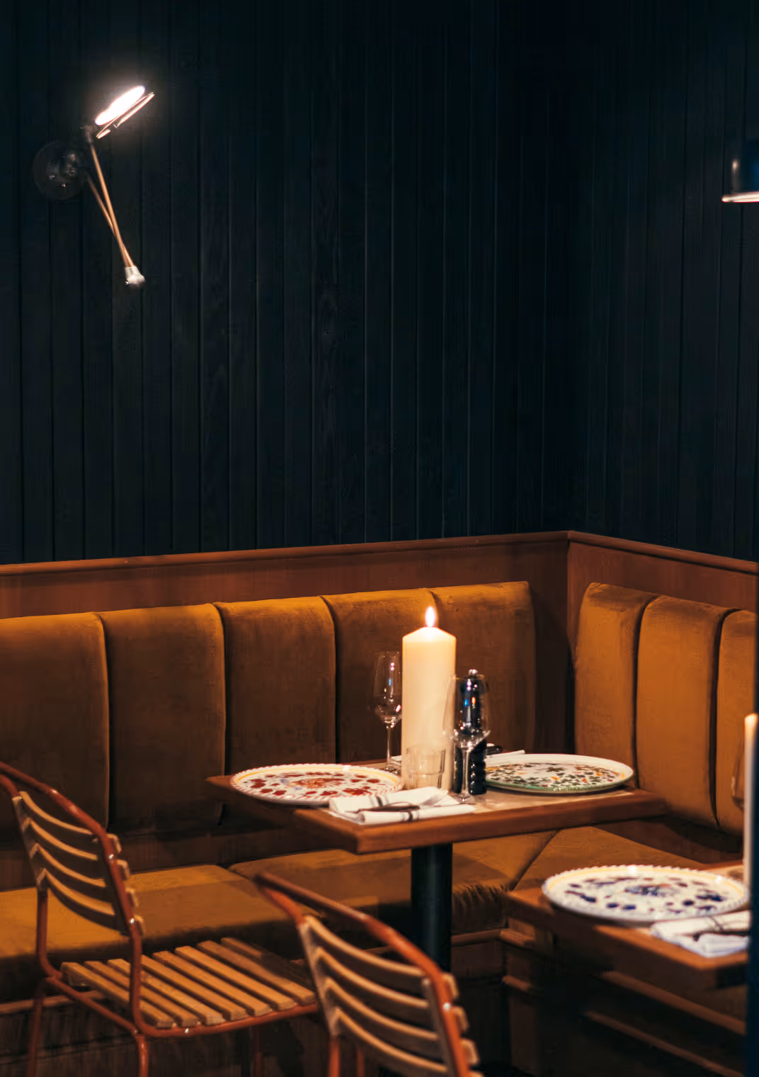 Intime Sitzecke mit dunkelblauer Wand, Samtbänken und Kerze im Italian Shot Glockenbach.