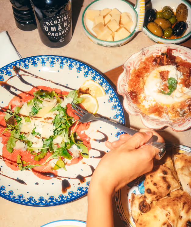 Vorspeisenteller im Italian Shot Glockenbach mit Carpaccio, Burrata und Oliven, aufgenommen aus der Vogelperspektive.