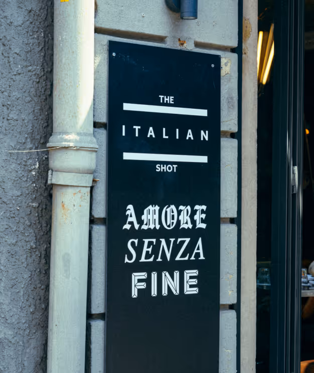 Eingangsschild des Italian Shot Maxvorstadt mit dem Schriftzug „Amore Senza Fine“.