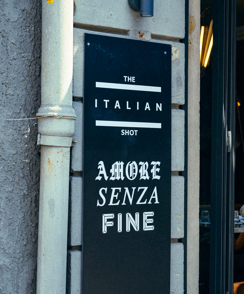 Eingangsschild des Italian Shot Maxvorstadt mit dem Schriftzug „Amore Senza Fine“.