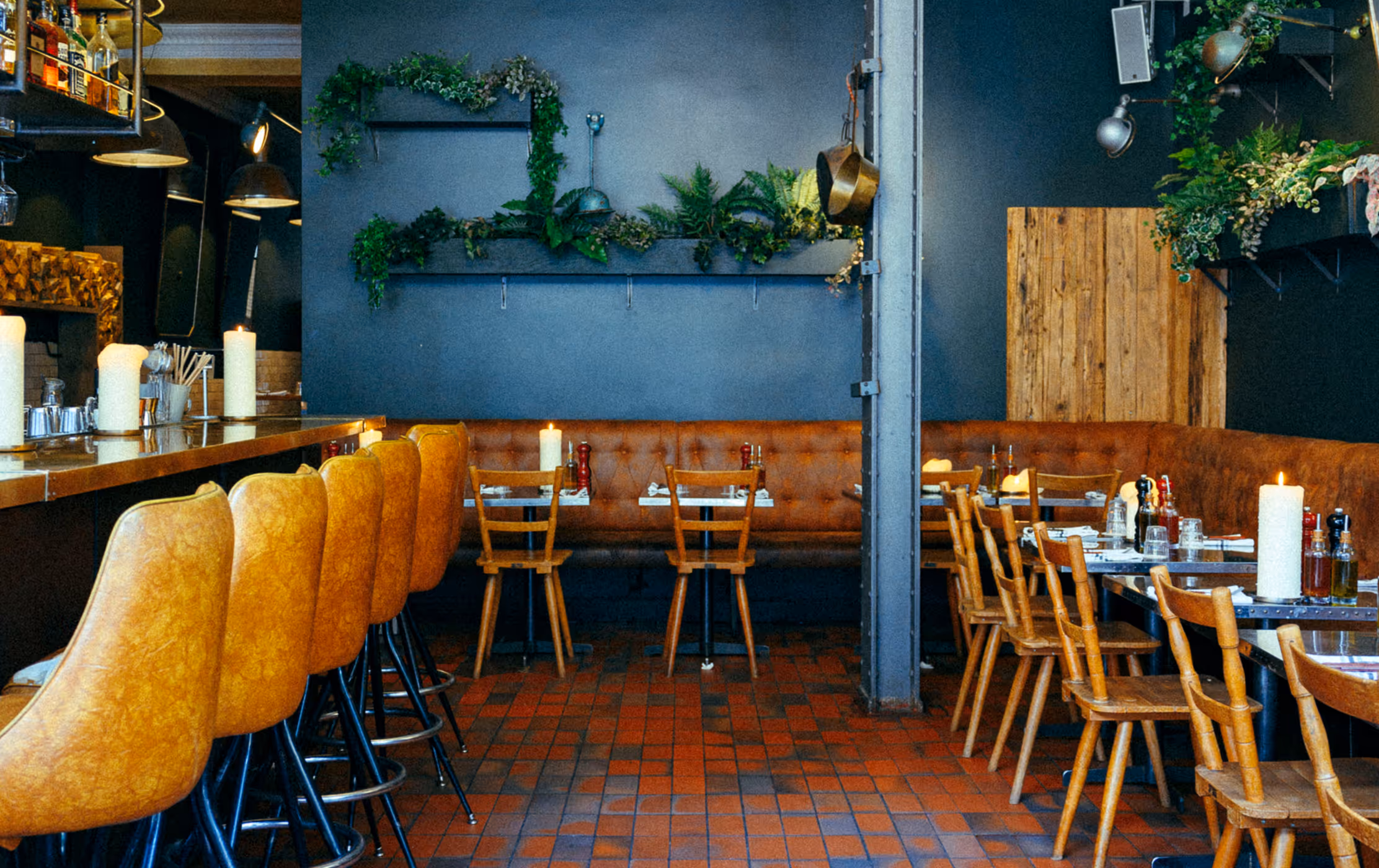 Innenraum des Italian Shot Maxvorstadt mit Bar, warmen Lederstühlen, Pflanzen und gedeckten Holztischen.