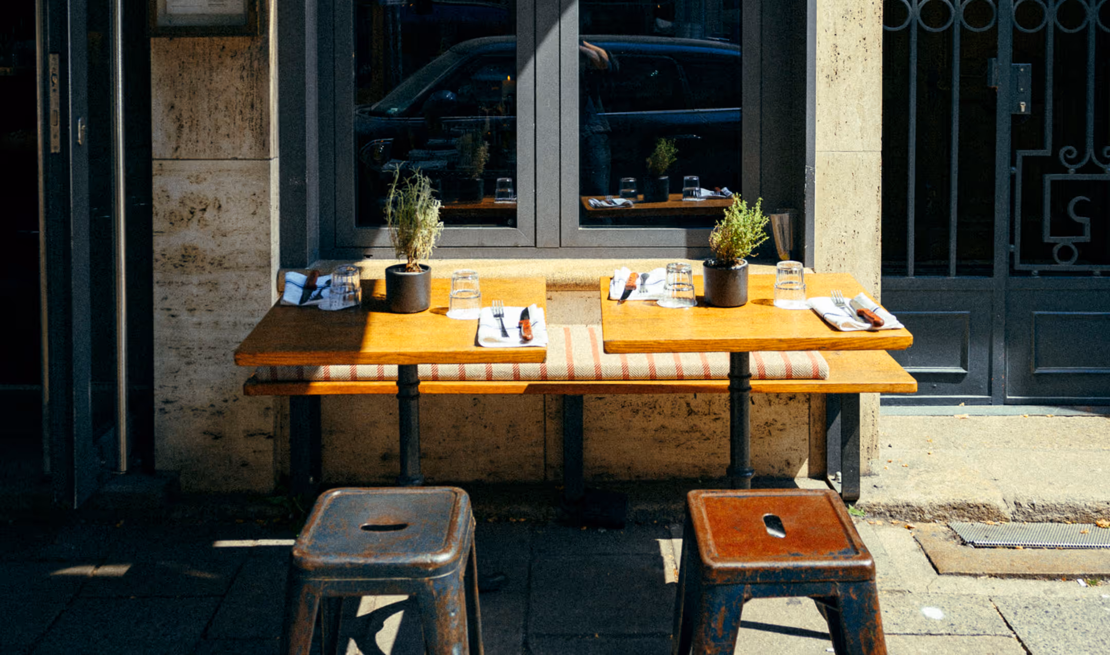 Zwei kleine Außentische mit Hockern vor dem Italian Shot Maxvorstadt, bereit für Gäste.