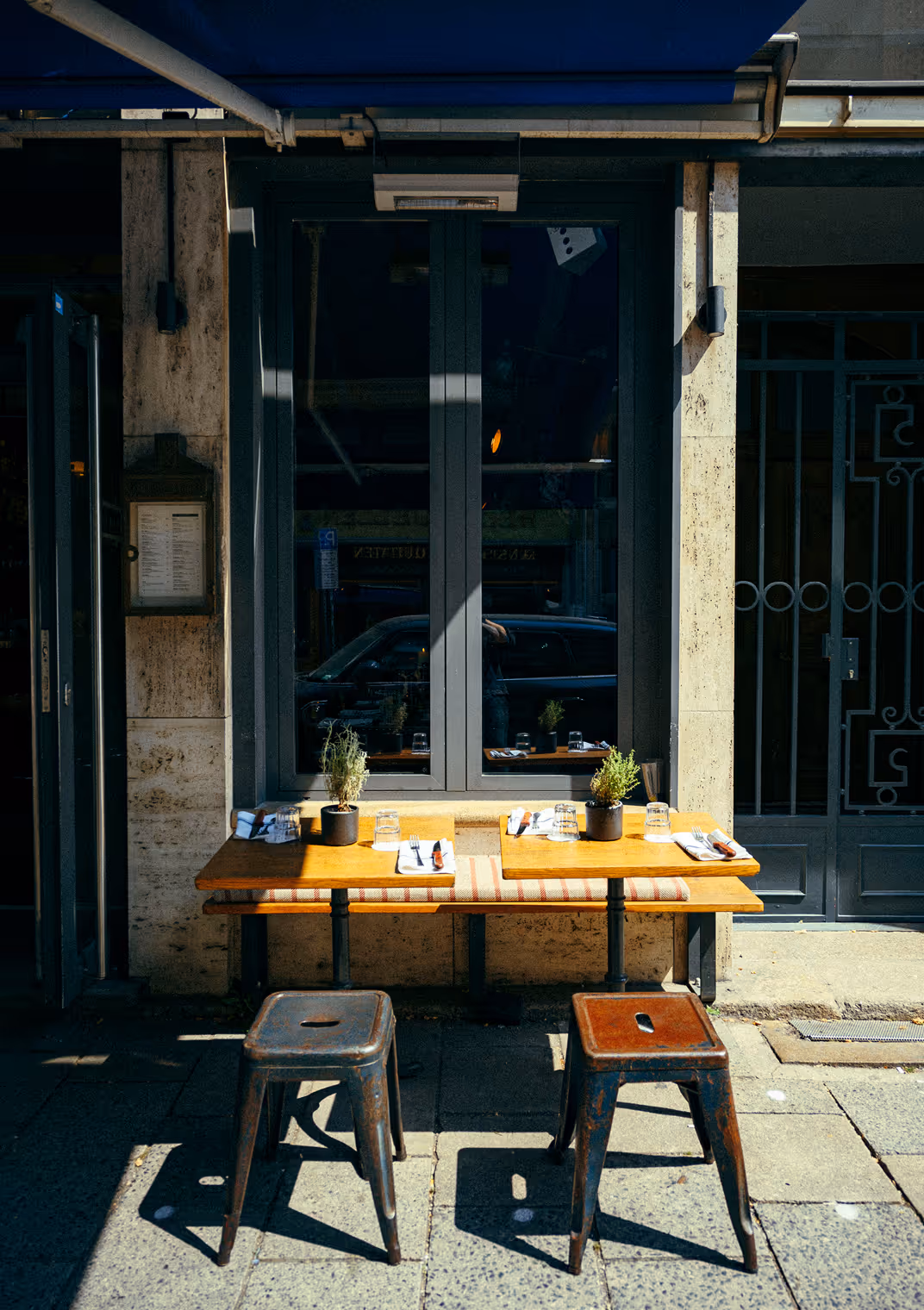 Zwei kleine Außentische mit Hockern vor dem Italian Shot Maxvorstadt, bereit für Gäste.
