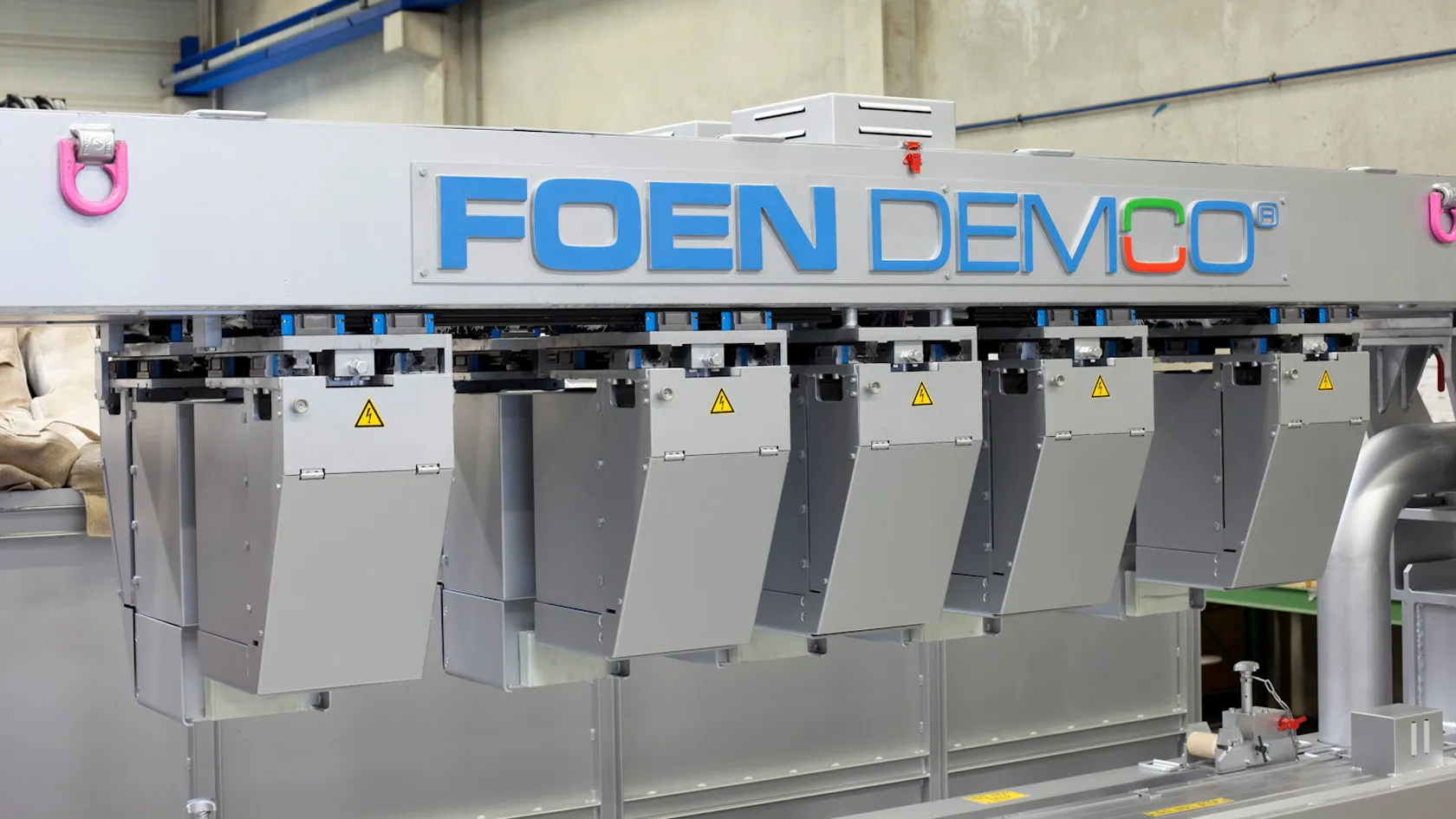 Industrial machine marked FOEN DEMCO in a factory environment.