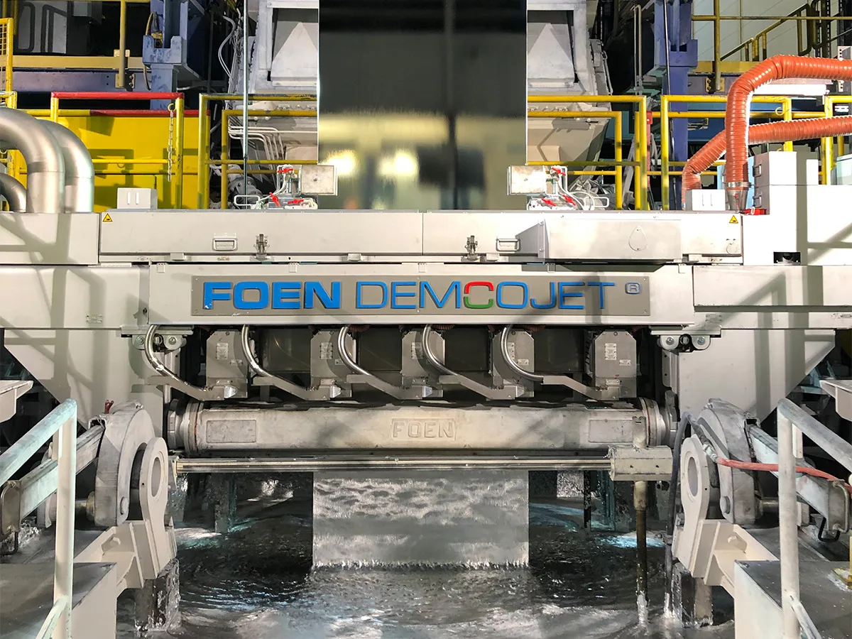 Industrial machine with the inscription FOEN DEMCOJET, water flows underneath.