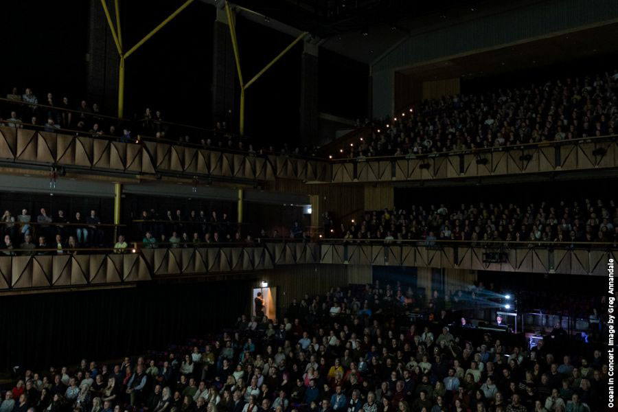 A theatre packed with a seated audience