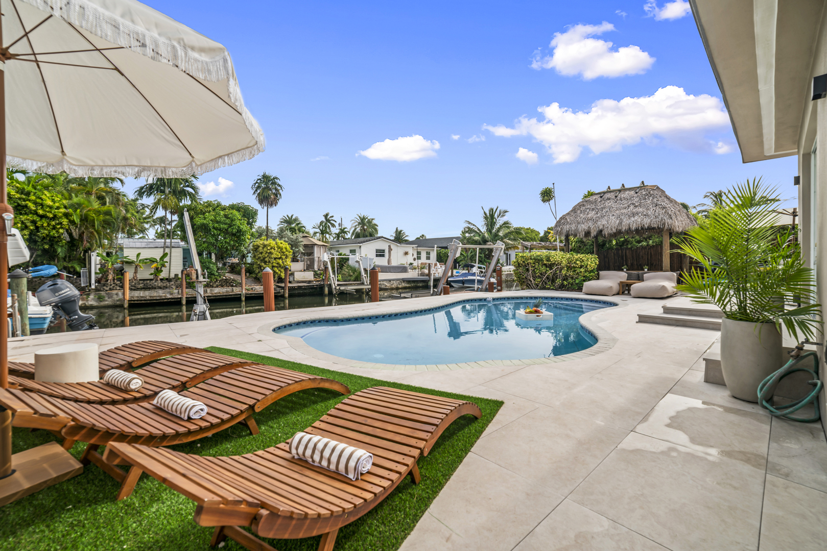 Sunny waterfront pool deck with loungers and a canal view at a Flight Mode home