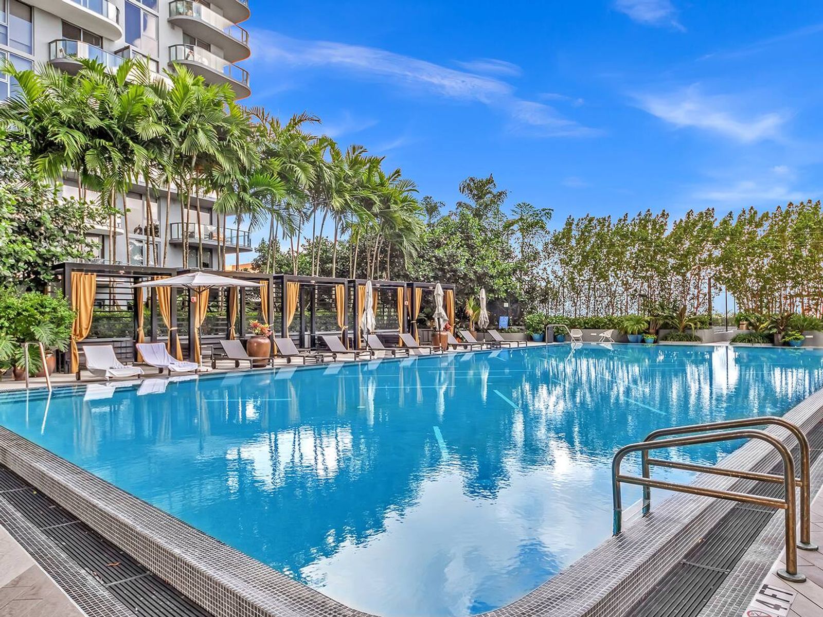 Resort-style pool deck with cabanas and palm trees at Hyde Midtown