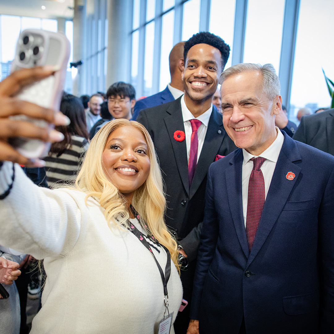 Three people smiling and posing for a selfie at an indoor event.