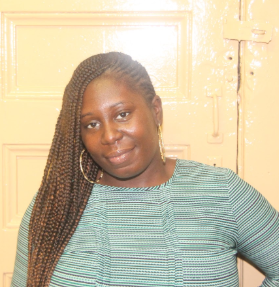 Ms. Wheeler smiling in front of a wooden door