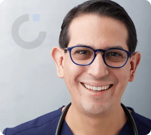 Dr. Carlos Quesada with a stethoscope, smiling in his medical office.