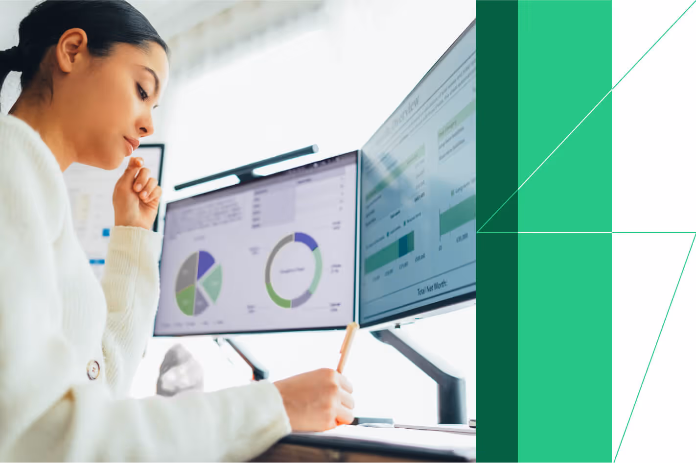 Woman analyzing data on two computer screens with pie charts and graphs for business finance insights.
