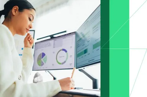 Woman analyzing financial data on dual monitors with pie charts and graphs at her desk.