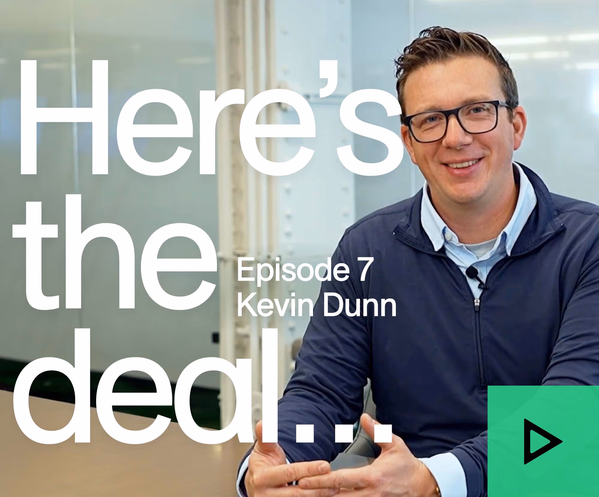 Smiling man with glasses and microphone in a navy jacket for podcast episode seven with Kevin Dunn.
