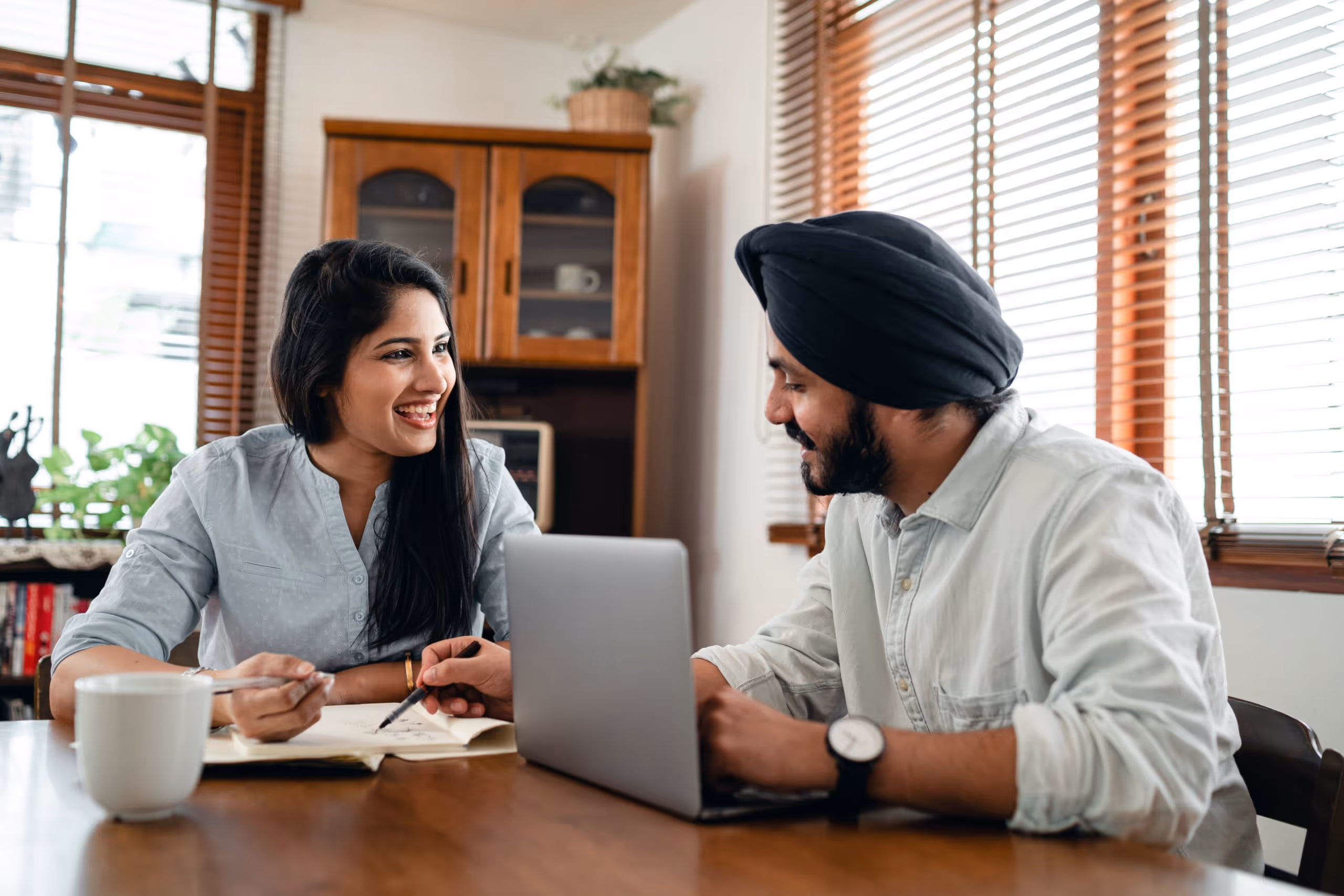 Couple working together on laptop and notebook in home office setting with warm natural light.