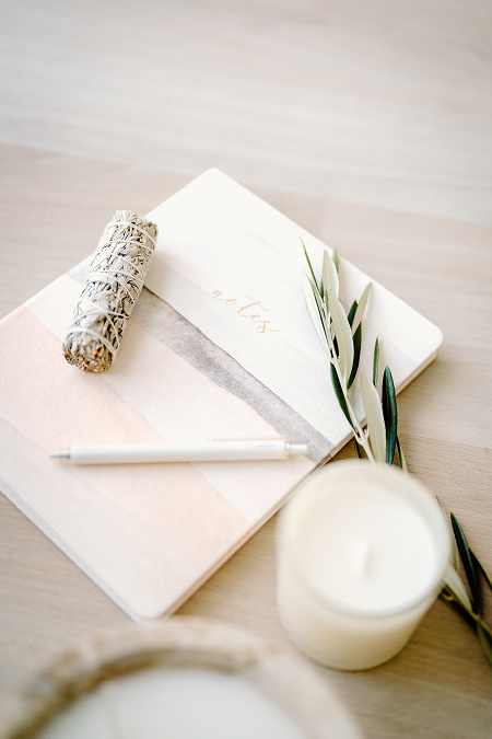 A notebook with sage on top and a candle.