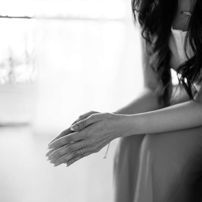 Hands placed together resting on knees