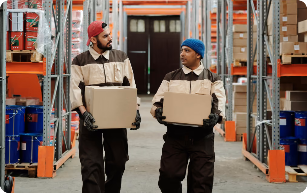 Warehouse workers carrying boxes down an aisle, representing flexible on-demand labor for warehouse operations through Spotwork.