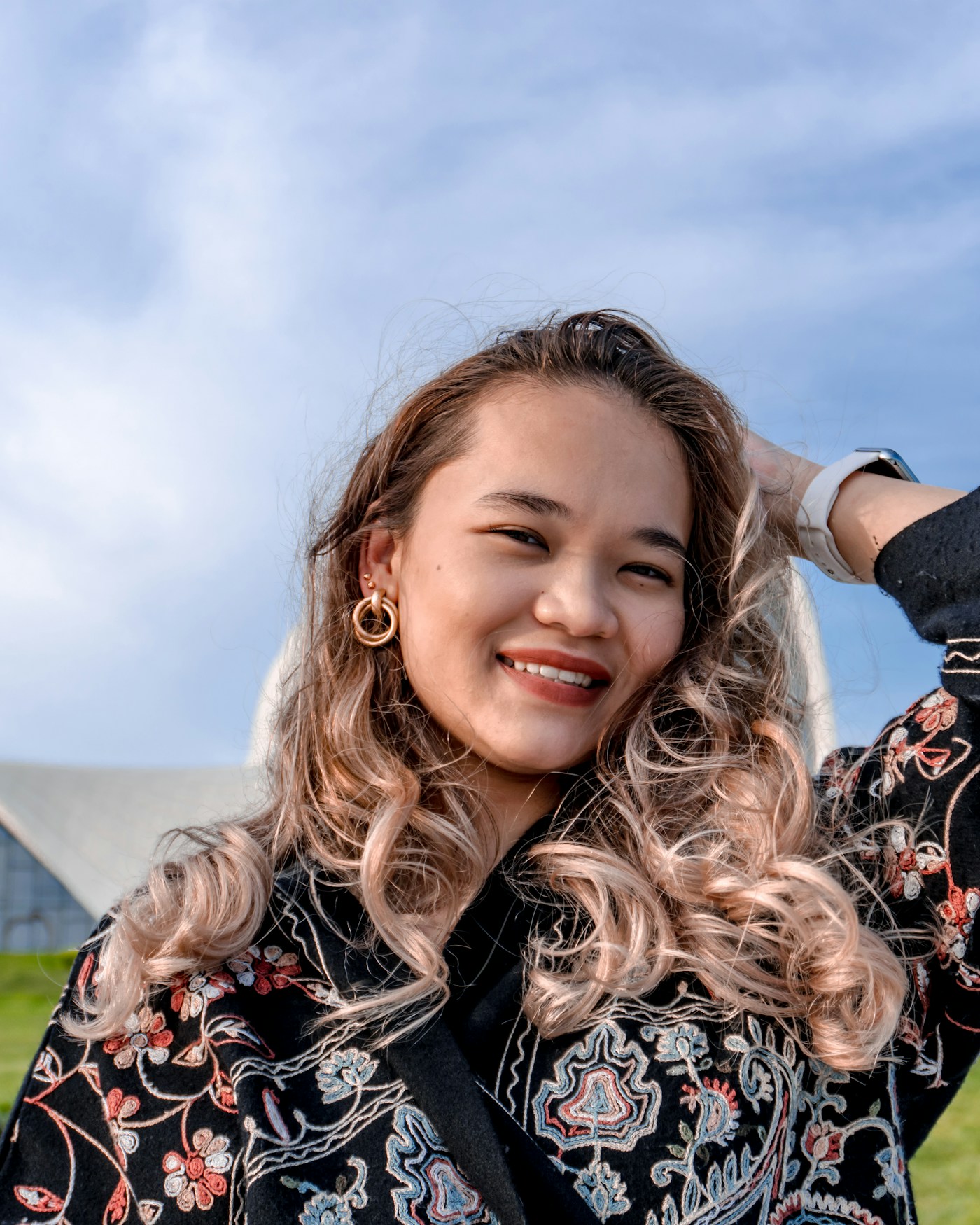 Woman outdoors with hand in her hair, relaxed and breezy