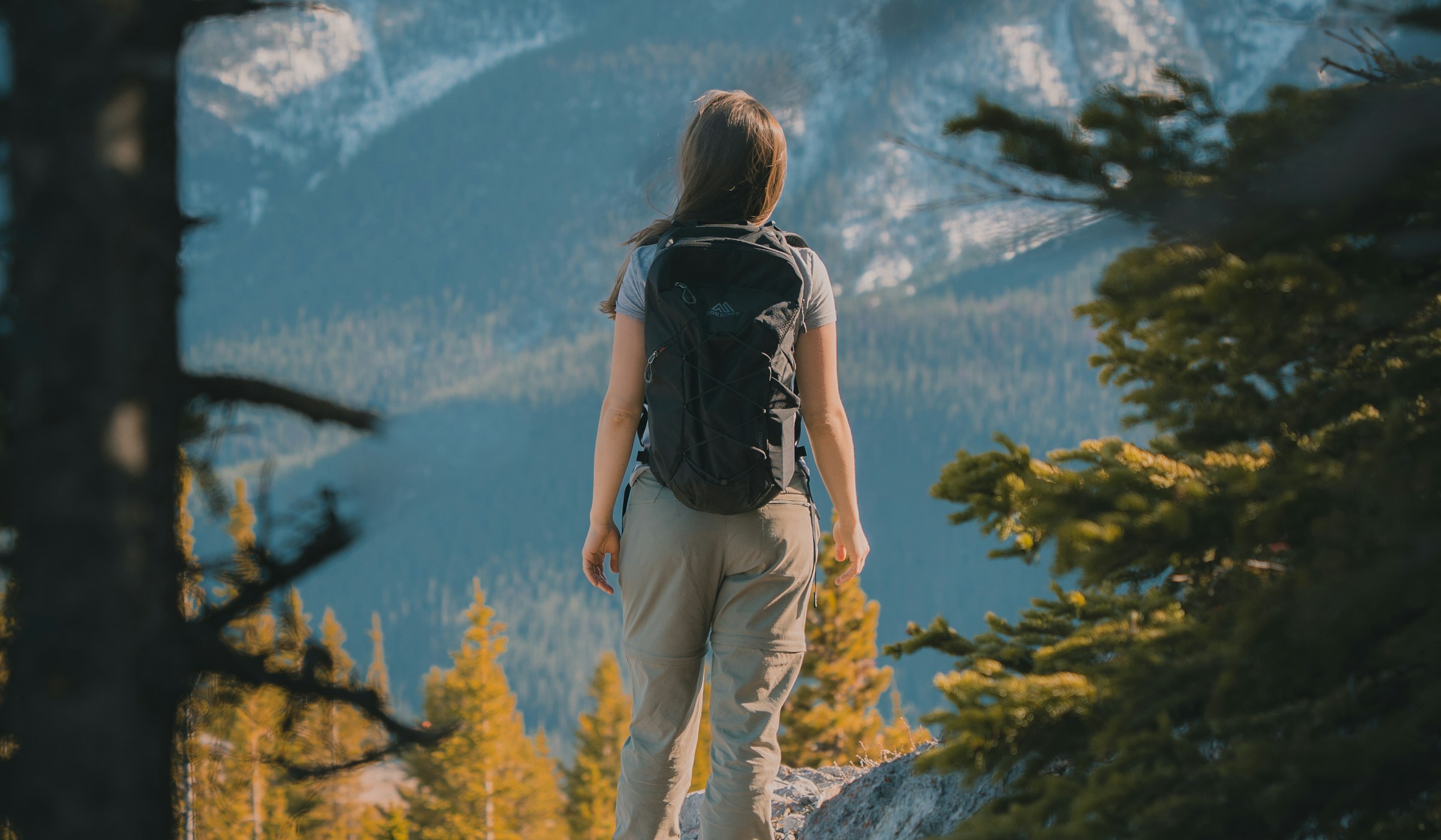 A woman hiking on a mountain trail, looking out over the valley