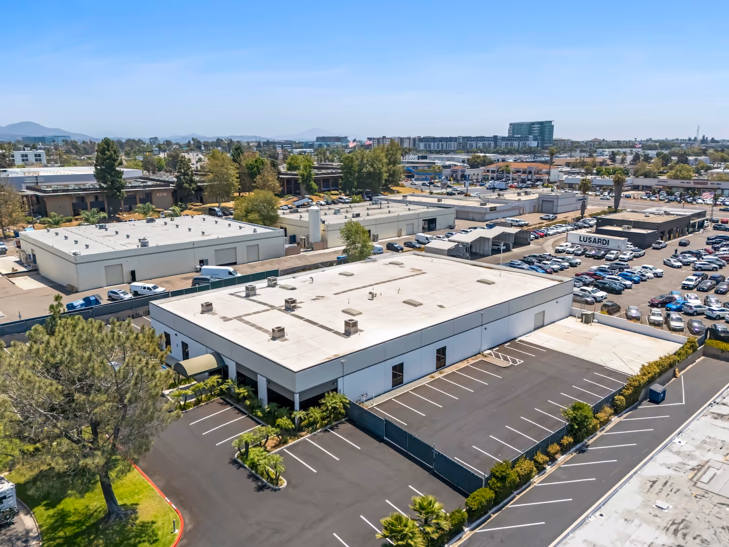 Aerial view of industrial complex with parking lot and surrounding urban landscape
