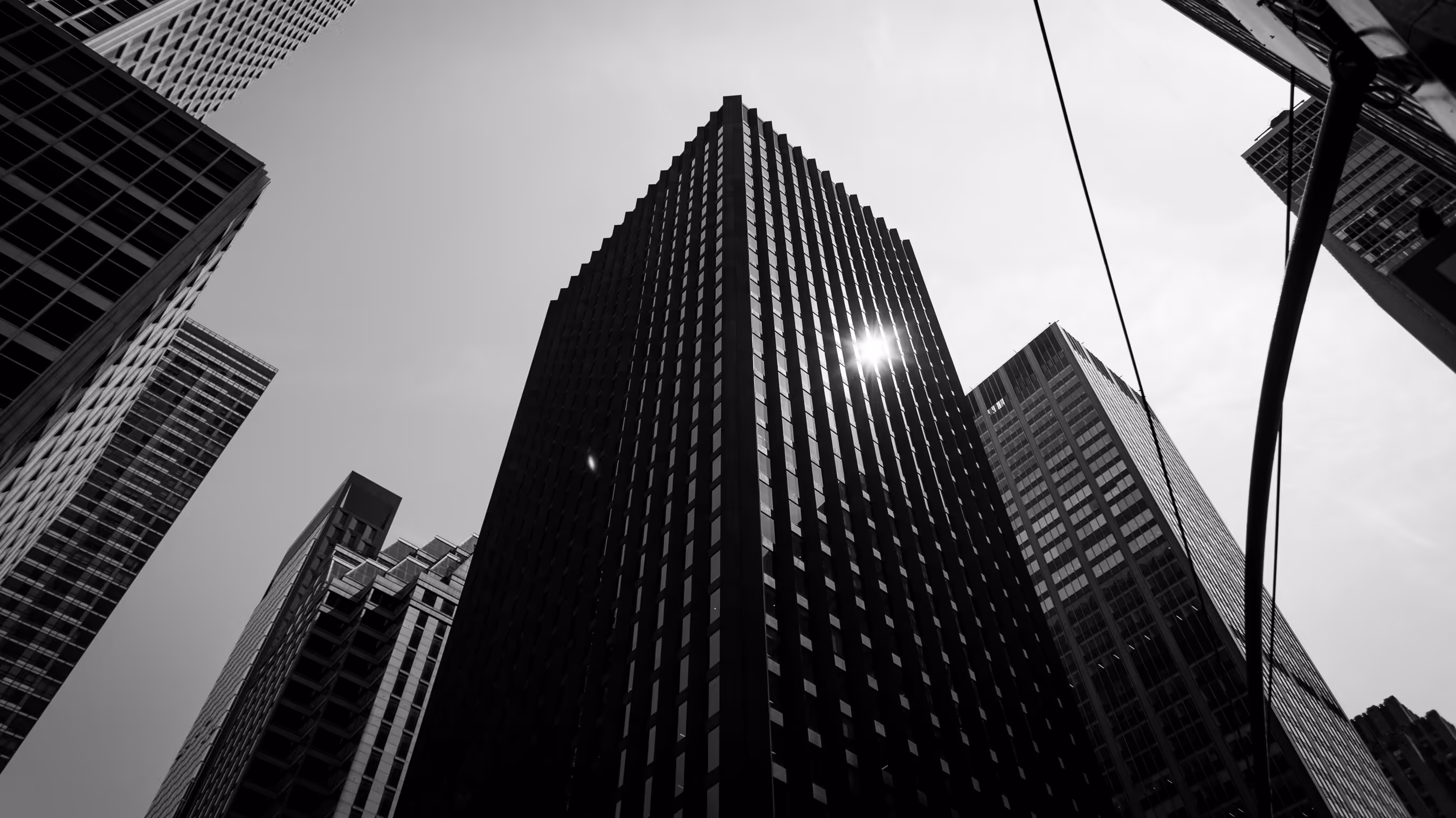 Black and white cityscape of tall skyscrapers reaching towards bright sky