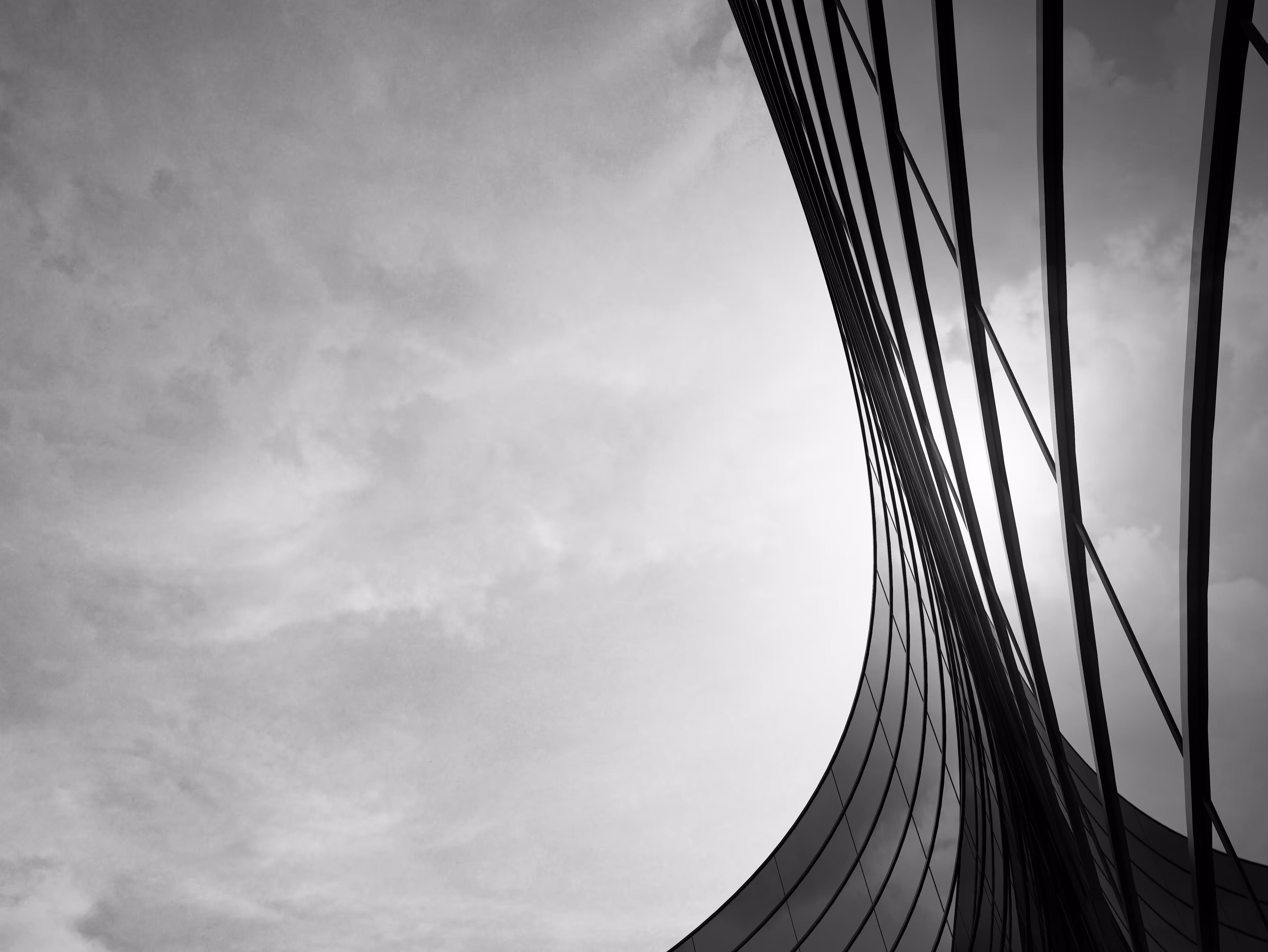 Curved modern architectural structure with dramatic lines against cloudy sky