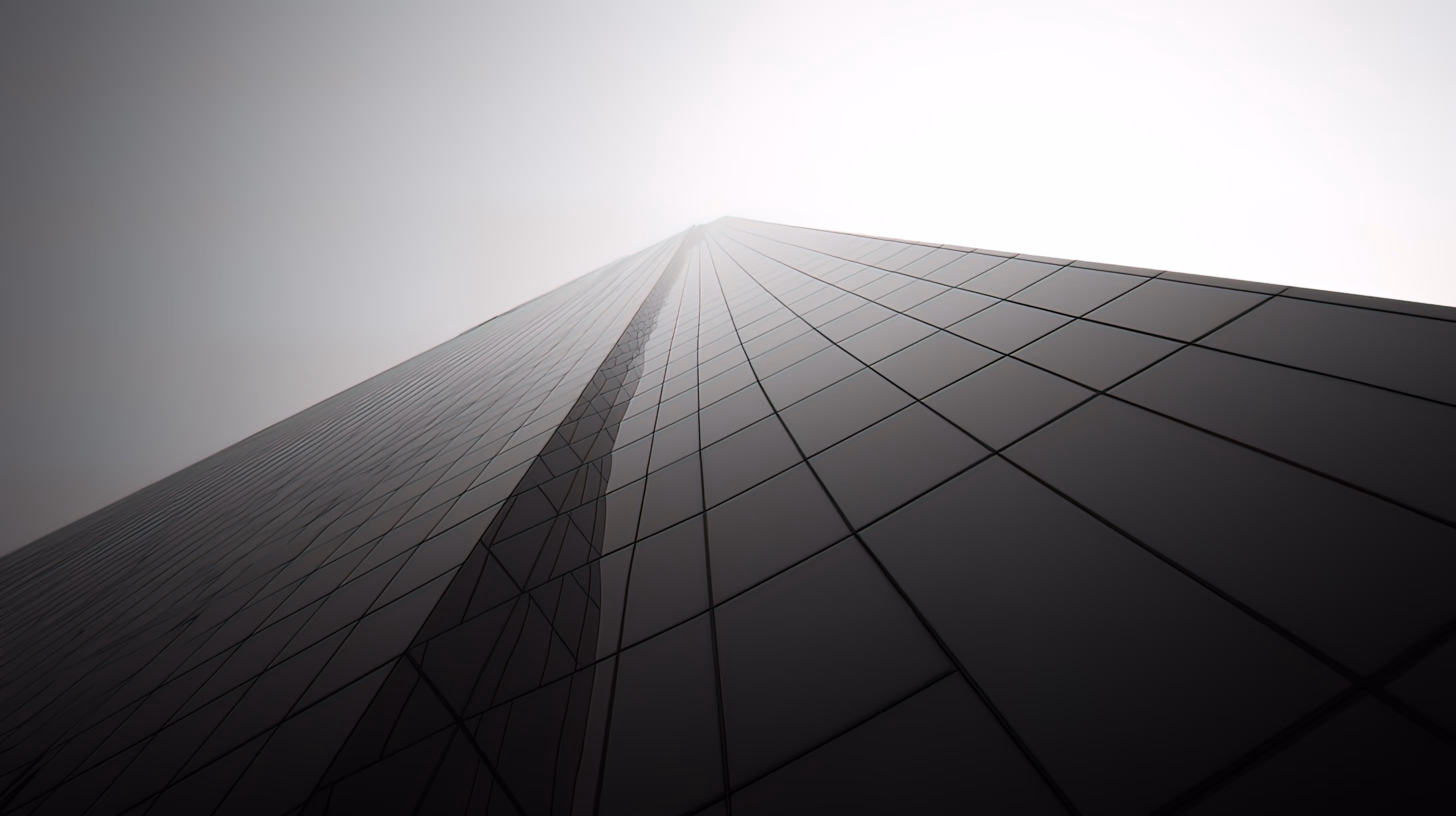 Sleek glass skyscraper rising into misty sky with geometric lines