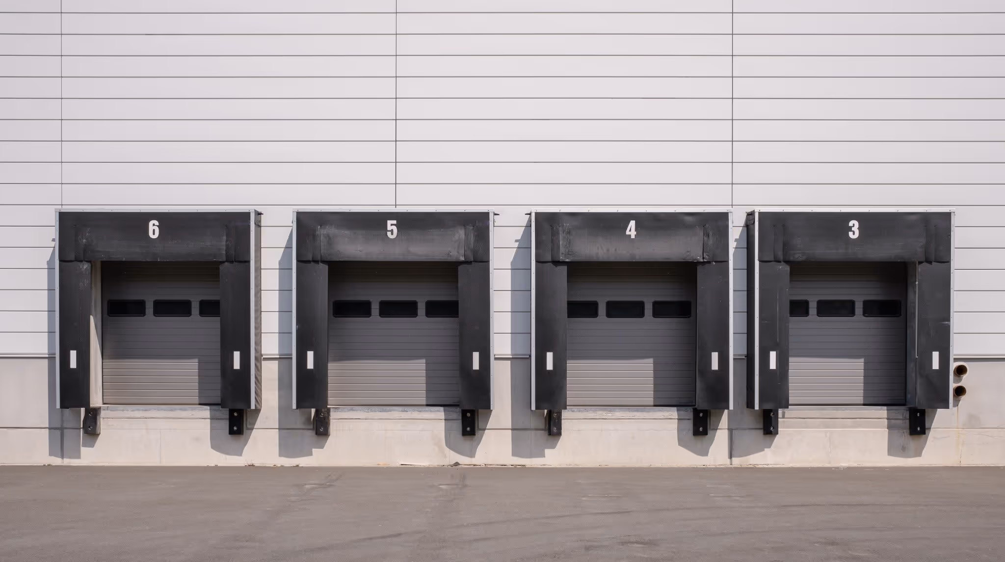 Four numbered loading dock doors on a warehouse exterior wall
