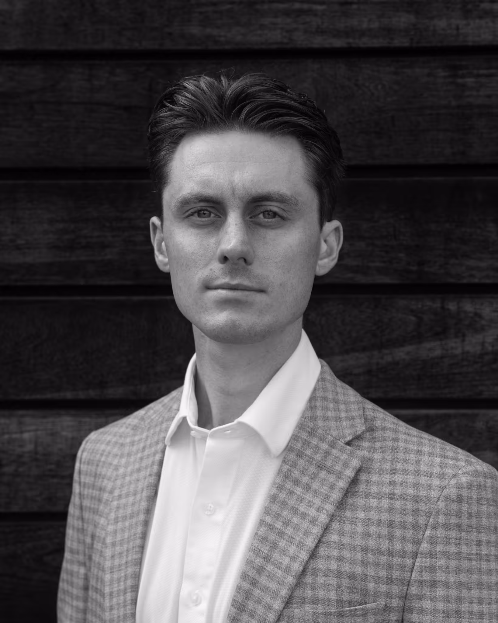 Black and white portrait of a person in a checkered suit jacket