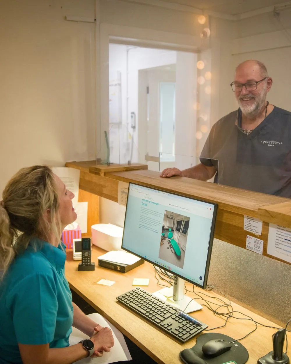 Two dental professionals smiling in the reception area.
