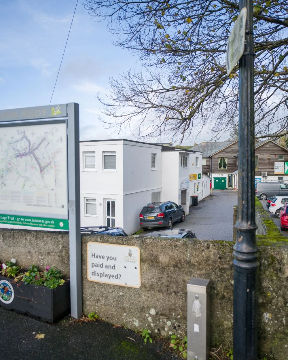 Cozy waiting room with beige armchairs and sofa, wood floor, a window with documents on the sill, and wall-mounted plants.