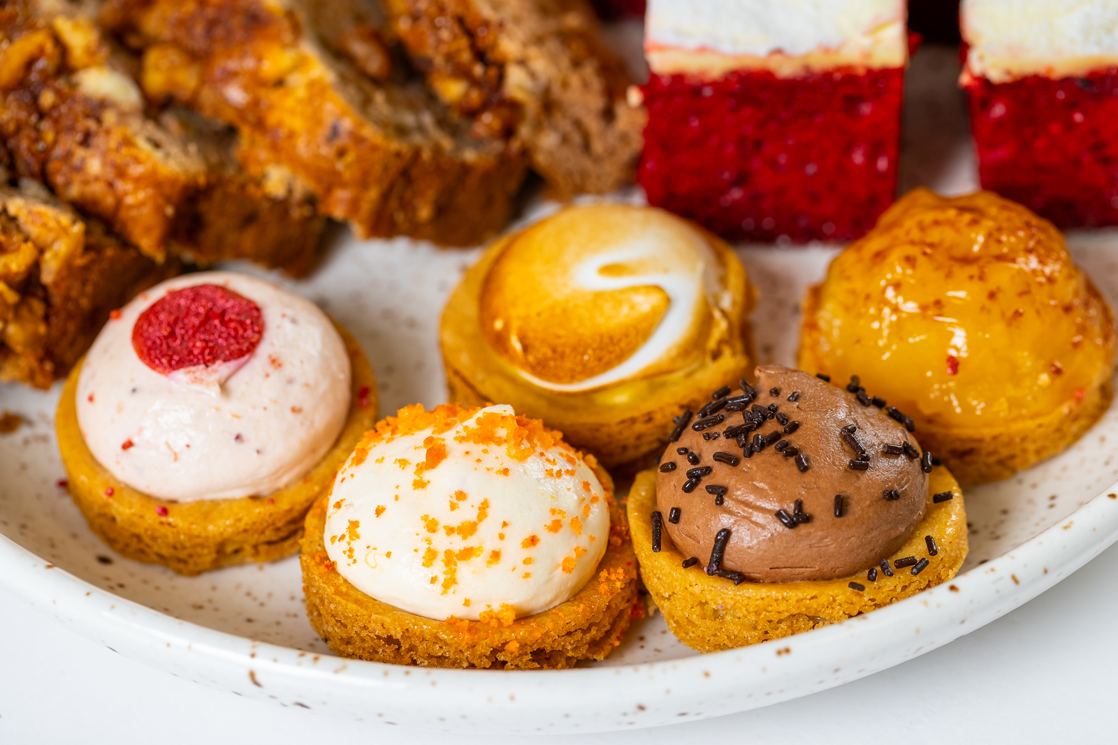 Bord met diverse mini-cupcakes met verschillende smaken en toppings, waaronder chocolade, fruit en room.