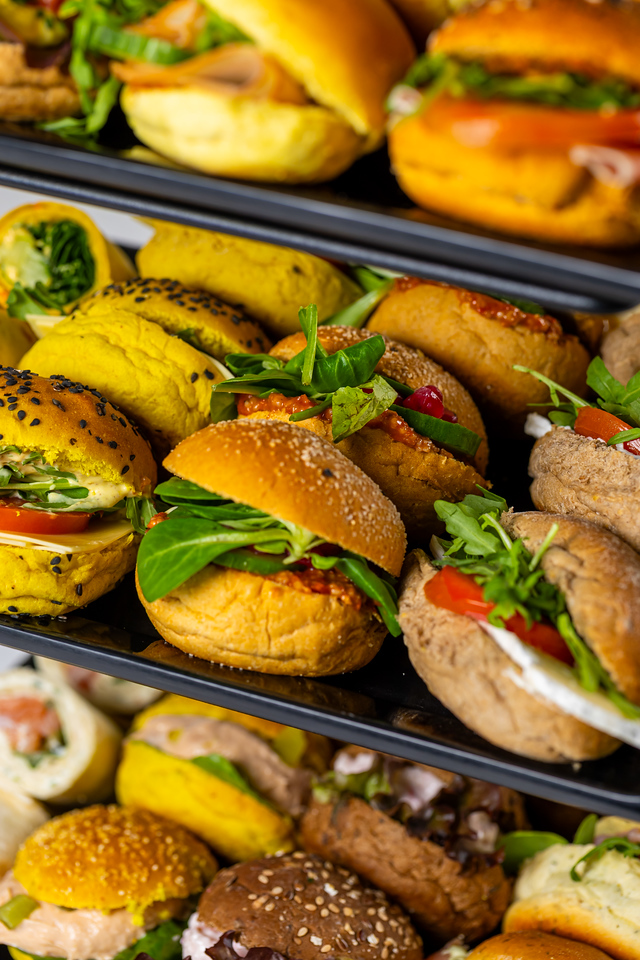 Drie verdiepingen met verschillende mini broodjes en wraps gevuld met verse groenten en bladgroenten.